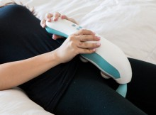 Woman lying on bed using the hi massager